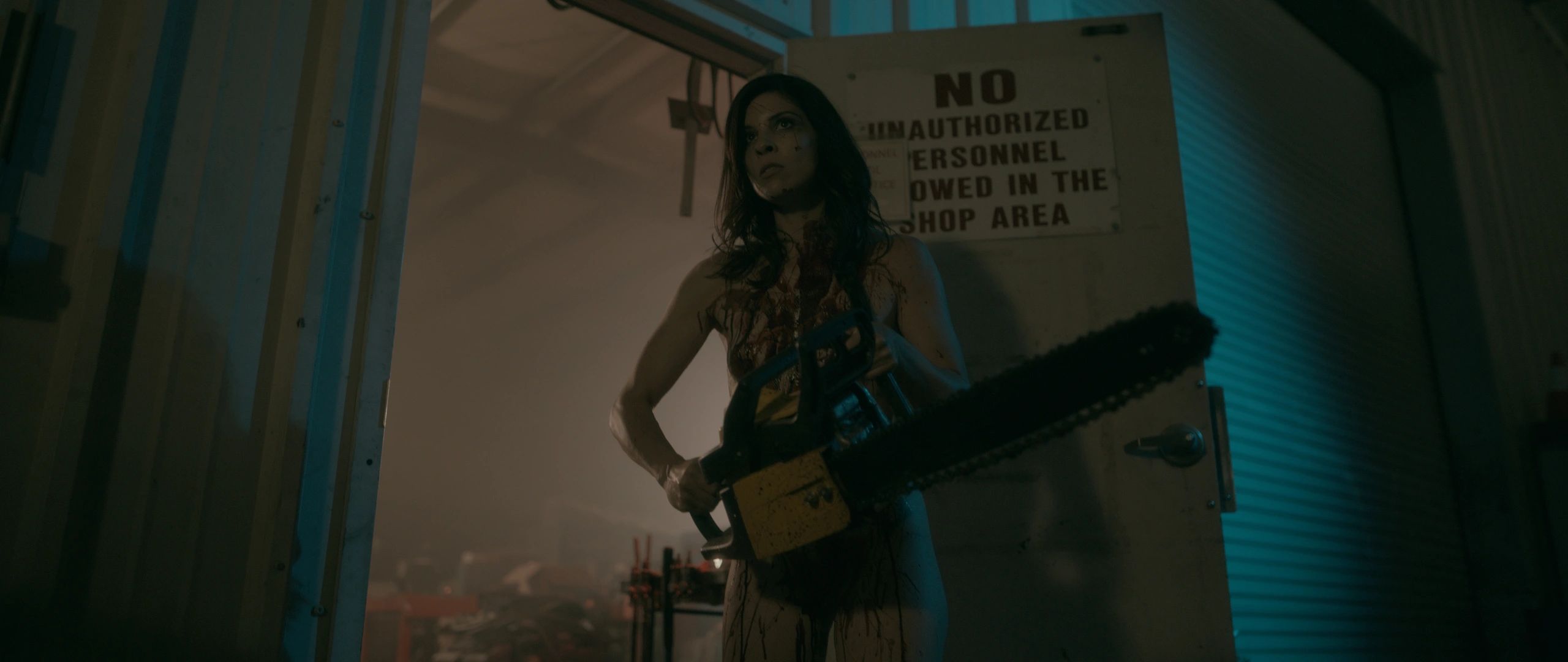 Barbara holding a chainsaw in a warehouse, cinematic still from Naked Zombie Girl is Back